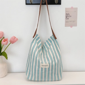 Detail of blue striped canvas tote with leather handle and branded woven label