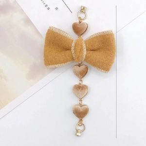 Plush mustard yellow bow and champagne heart pendant charm with gold metal clasp detail