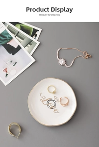 Detail view of golden rings, sunflower bracelet and hoop earrings on a ceramic tray
