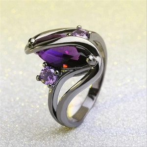 Macro detail of gunmetal ring featuring purple marquise-cut stone and side crystals