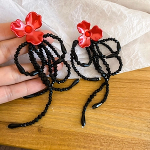 Vue détaillée de boucles d'oreilles fleur rouge avec glands en perles noires