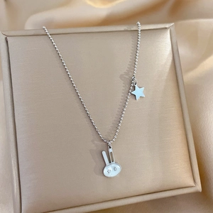 Detailed macro view of a silver rabbit and star pendant necklace on bead chain