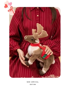 Close-up of a soft reindeer plush toy being embraced, showing its festive red and green collar