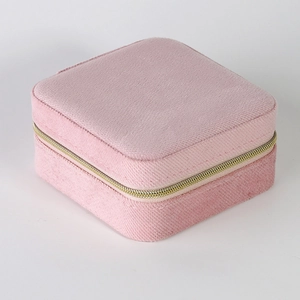 Top-down view of a pink velvet square jewelry box with gold metal zipper and texture
