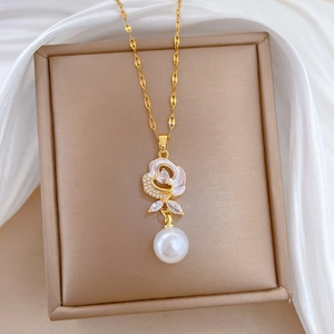 Detail of luxury gold flower necklace with white shell, zircon inlay and hanging pearl charm
