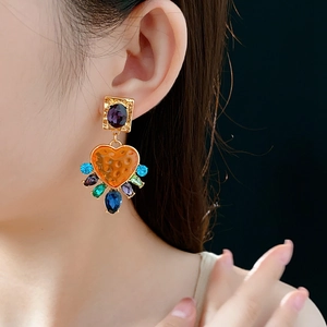Détail de boucles d'oreilles cœur vintage serties de strass colorés sur modèle