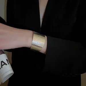 Detail of wide hammered gold metal cuff with irregular geometric texture on a blazer