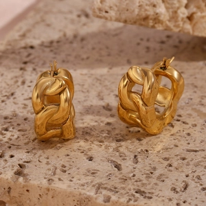 Macro detail of chunky gold plated chain link earrings on a textured stone surface