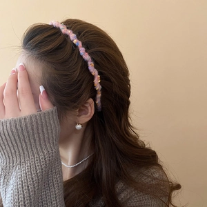 Close-up of a colorful wool woven headband on brown hair with elegant pearl accessories