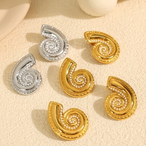 Detail of vintage spiral earrings in gold and silver finish with inlaid mini pearls