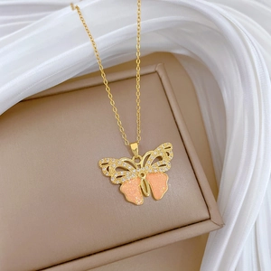 Detail of gold butterfly necklace featuring pink glitter wings and zircon accents