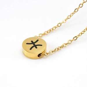 Dettaglio di una collana con ciondolo zodiacale dorato e simbolo dei Pesci nero su catena a O