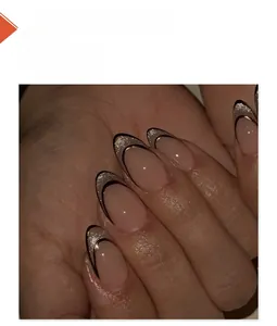 Close-up of nude pink almond nails with black and gold French tips and glitter