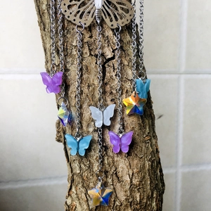 Detail of metal butterfly suncatcher with crystal pendants hanging on a tree branch