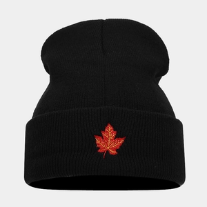 Close-up of a black knit beanie featuring a vibrant red maple leaf embroidery detail