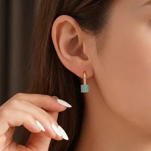 Elegant 18K gold hoop earrings with turquoise stone cylinder pendant on female model