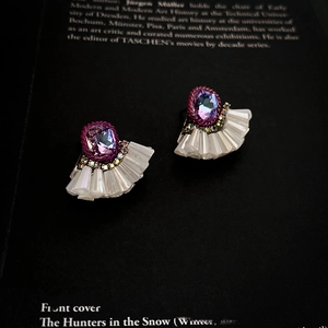 Macro detail of fan-shaped earring with purple gemstone and colorful crystal inlay