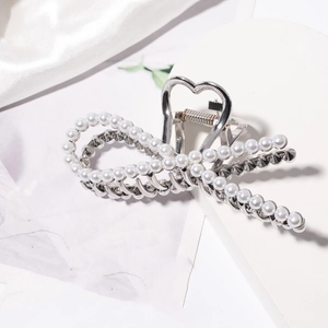 Detail view of large silver metal hair claw with pearls and heart-shaped handle design