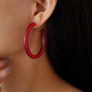 Close-up of translucent dark red resin C-shape hoop earrings on a model profile