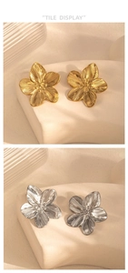 Macro detail of gold and silver five-petal flower earrings with textured metallic finish