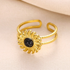 French vintage sunburst gold ring with central black gemstone on beige fabric