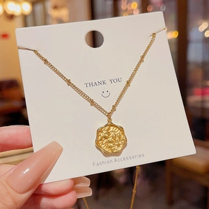Detail of a vintage golden irregular pendant with floral relief on a jewelry card