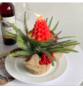 Detail of red Christmas tree candle with berries and snow effect on a white plate