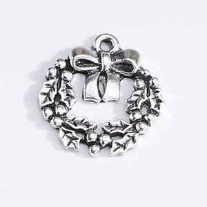 Detailed macro view of a silver Christmas wreath charm with holly leaves and bow knot