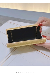Detail of golden pleated evening bag with metal frame, black lining and chain strap