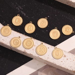 Detail of assorted 18K gold plated stainless steel letter pendants with textured edges