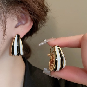 Retro schwarz-weiß gestreifte Tropfenohrringe in Gold-Finish getragen von einem Modell