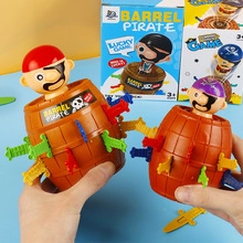 Close-up of hands holding colorful pirate barrel games with plastic swords and packaging