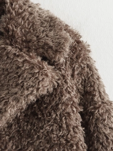 Close-up of curly brown faux fur texture on a stylish French design jacket