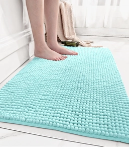 Close-up of feet on a thick light blue chenille bath mat with non-slip texture