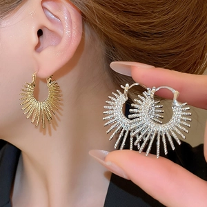 Detail view of round radial sunburst textured huggie earrings in gold and silver finish