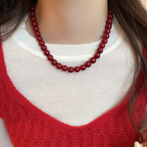 Close-up of a minimalist burgundy glass bead necklace worn on a female collarbone