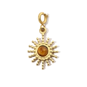 Detail of a golden sunburst pendant with a brown tiger eye stone on a white background