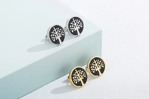 Detail view of tree of life earrings in gold and silver finish with black enamel inlay
