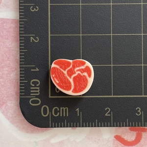 Detailansicht eines 1 cm großen Herz-Resin-Anhängers in Fleischoptik auf einer Matte