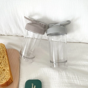 Close-up of portable plastic sports bottles with convenient flip-top handles on white fabric