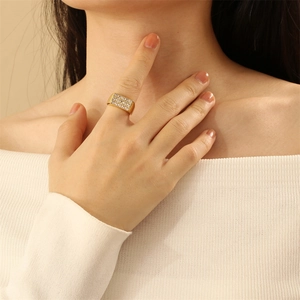 Close-up of wide gold ring set with multiple rows of rectangular zircons on model hand
