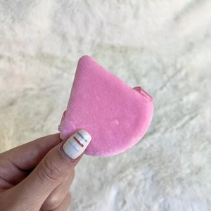Close-up of a mini pink triangular velvet makeup sponge held by hand for precision