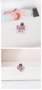 Détails de boucles d'oreilles cœur et nœud en zircon rose sur boîte texturée