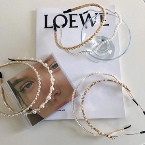 Detail view of pearl headbands with layered gold chains and rhinestones on desk