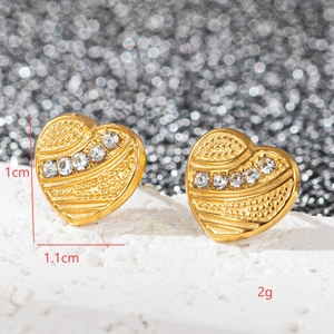 Vue macro de boucles d'oreilles cœur dorées avec cristaux et détails de taille 1,1 cm