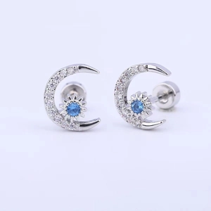 Macro detail of moon and star earrings with sparkling zircon stones and blue center gem