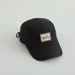 Detail of a black five-panel camper cap with a bear embroidery patch and breathable side vents