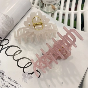 Detailed view of large acrylic flower hair claws in cream and translucent pink colors