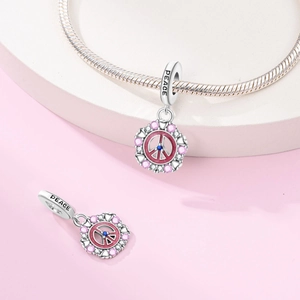 Macro shot of silver peace charm with pink enamel and gems on a snake bone chain
