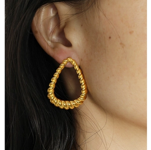 Close-up of model wearing chunky golden twisted rope drop earrings in a pear-shaped design